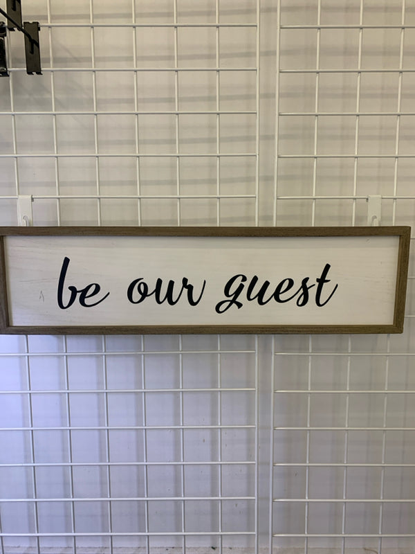 "BE OUR GUEST" BLACK LETTERS ON WHITE SIGN.