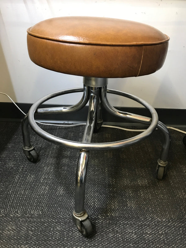 SHORT ROUND BROWN FAUX LEATHER STOOL ON WHEELS.