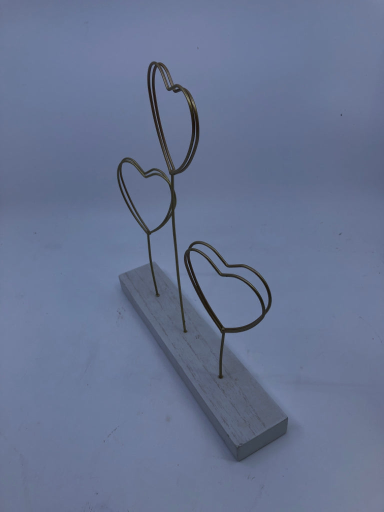 GOLD METAL HEART PHOTO HOLDER ON WHITE WOOD BLOCK.