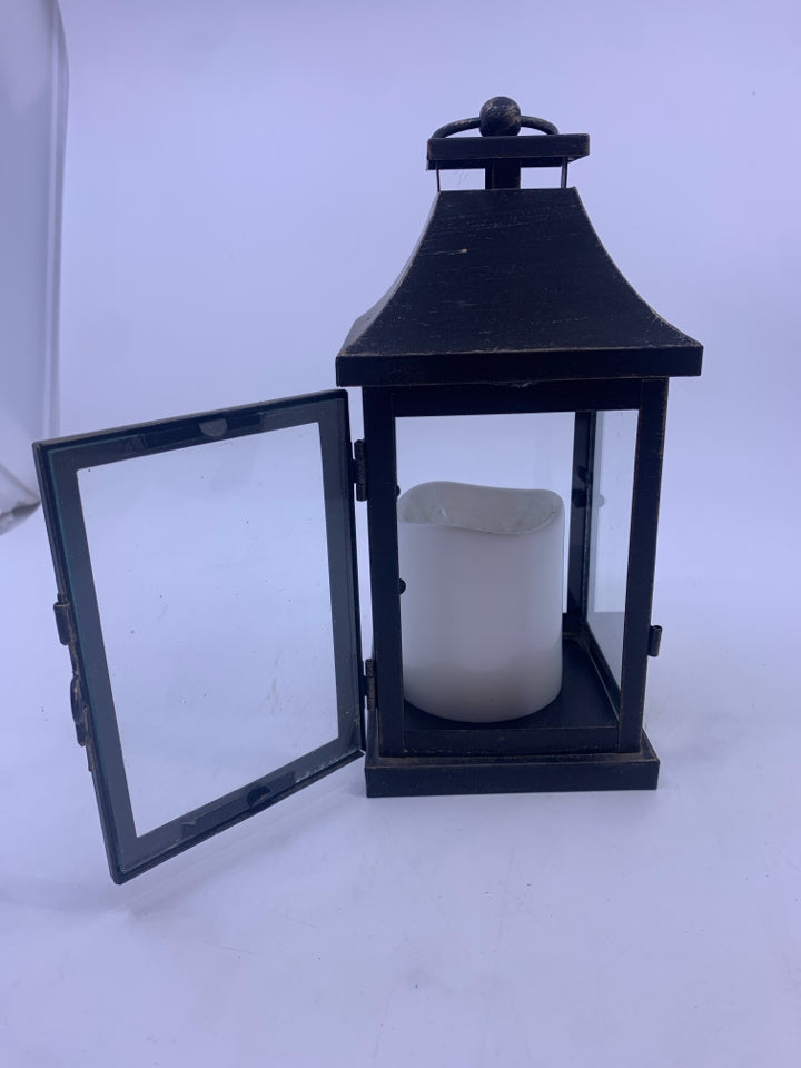 BLACK DISTRESSED LANTERN WITH ELECTRIC WHITE CANDLE.