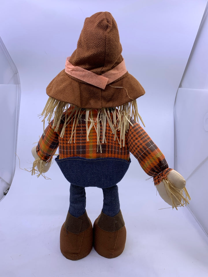 STANDING SCARECROW IN ORANGE SHIRT JEANS OVERALLS.