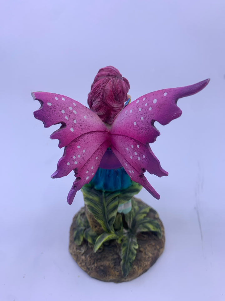 RESIN FAIRY SITTING ON A STUMP W/ PURPLE WINGS.