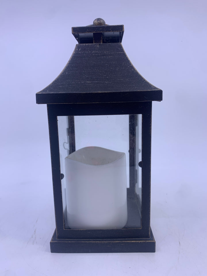 BLACK DISTRESSED LANTERN WITH ELECTRIC WHITE CANDLE.