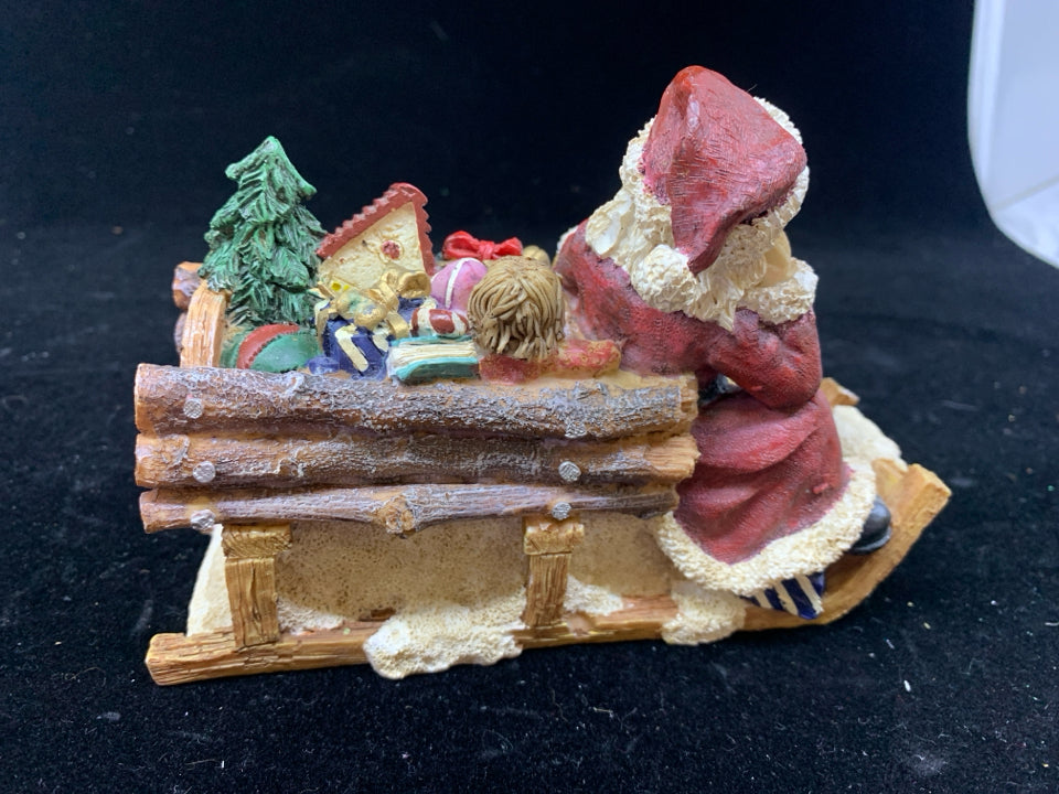 SANTA SITTING ON SLEIGH W TOYS.