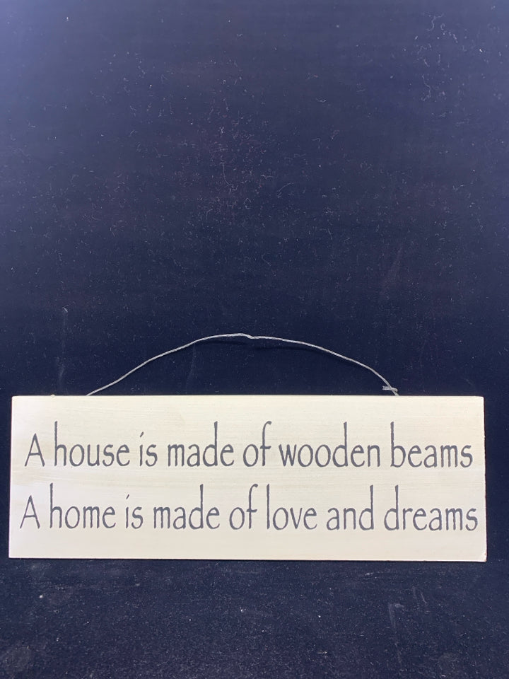 A HOUSE IS WHITE WOOD WALL ART W/ BLACK LETTERS.