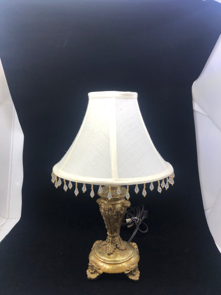 GOLD EMBOSSED FOOTED SCROLL DETAIL BASE LAMP W/ CREAM BEADED SHADE.