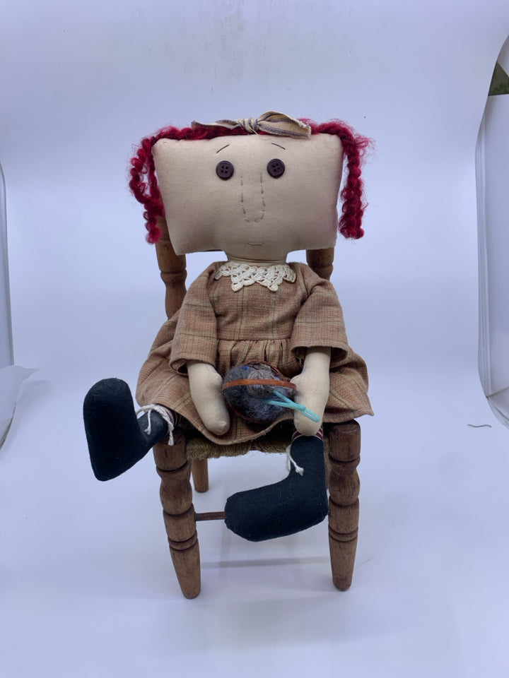 PRIMITIVE GIRL W/BASKET OF YARN SITTING IN A CHAIR.