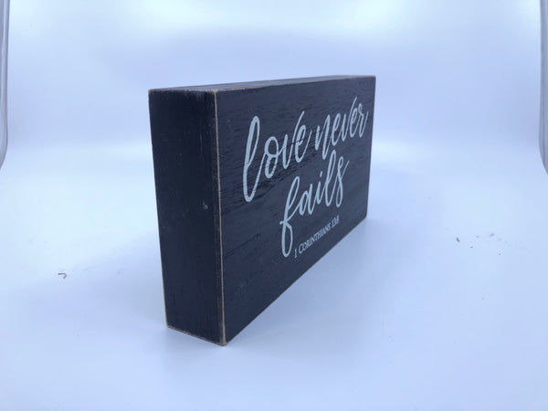 "LOVE NEVER FAILS"  BLACK WOOD WALL HANGING.