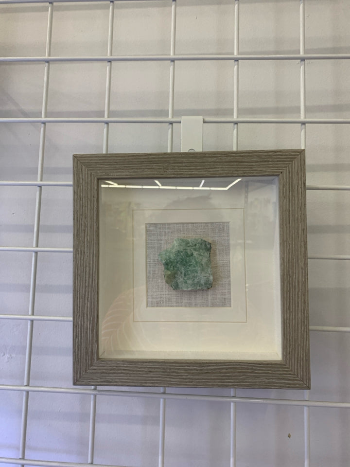 GREEN CRYSTAL IN SHADOW BOX WITH GRAY FRAME.