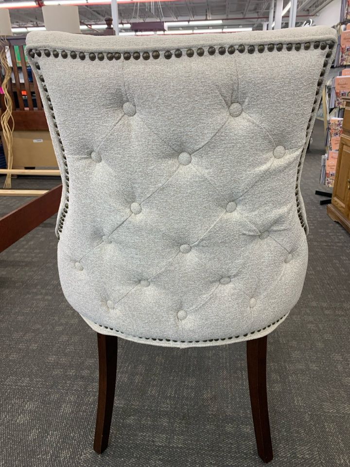 UPHOLSTERED CREAM CHAIR W/DARK WOODEN LEGS.