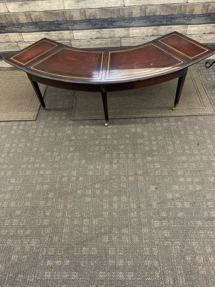 VTG DARK WOOD CRESCENT SHAPE COFFEE TABLE ON WHEELS.