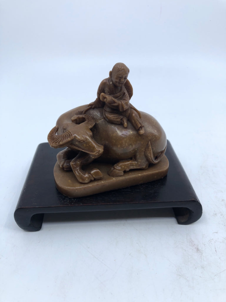 BROWN BULL & MAN FIGURINE ON WOOD SLAB.