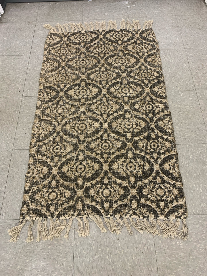 BLACK AND TAN PATTERNED AREA RUG.