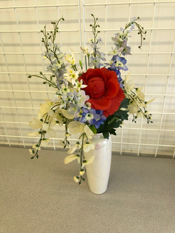 WHITE IRIDESCENT VASE WITH RED WHITE AND BLUE FLOWERS.