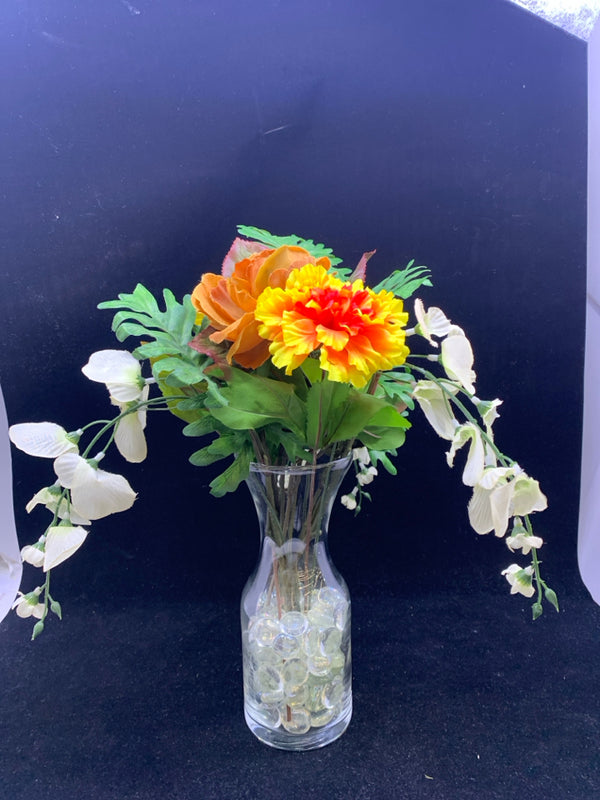 CLEAR GLASS VASE WITH YELLOW BROWN AND WHITE FLOWERS.