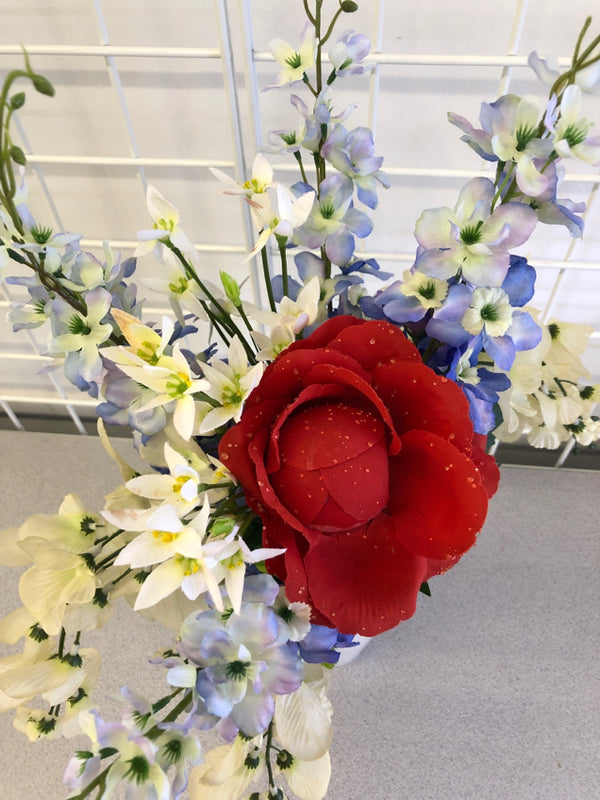 WHITE IRIDESCENT VASE WITH RED WHITE AND BLUE FLOWERS.