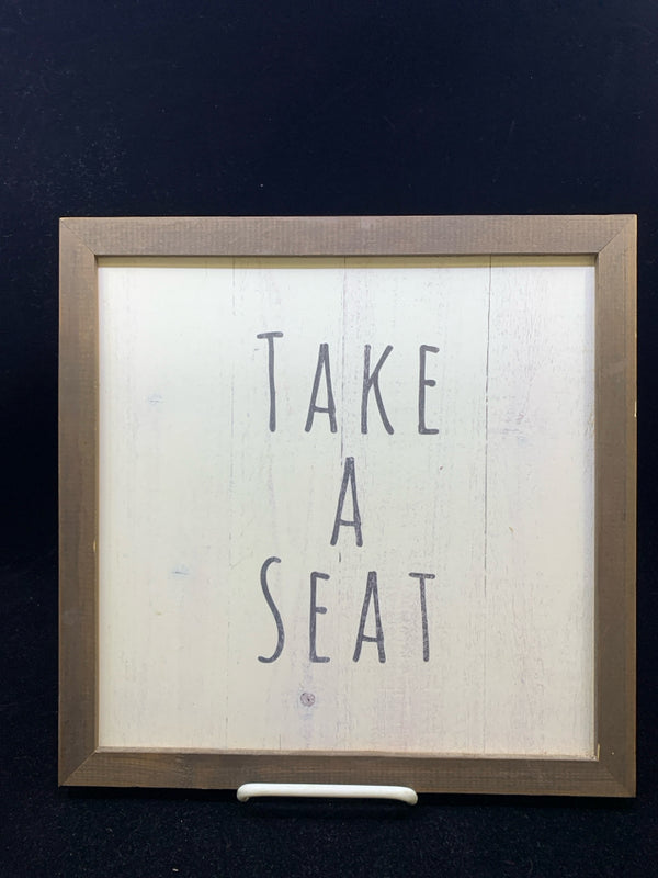 "TAKE A SEAT" WHITE BACKGROUND W/ DARK WOOD FRAME.