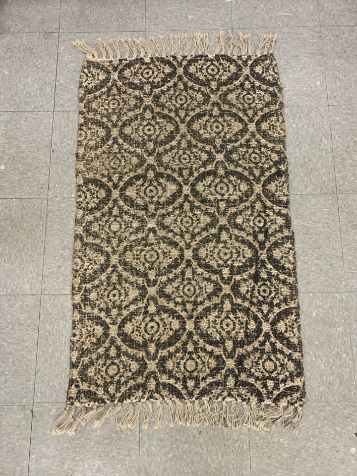 BLACK AND TAN PATTERNED AREA RUG.