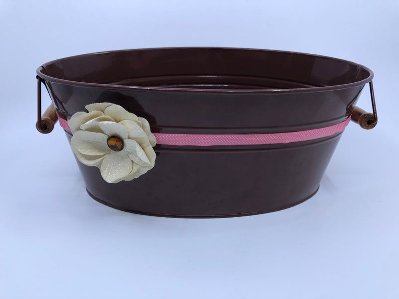 BROWN TIN OVAL BUCKET W/ SIDE HANDLES AND WHITE FLOWER.