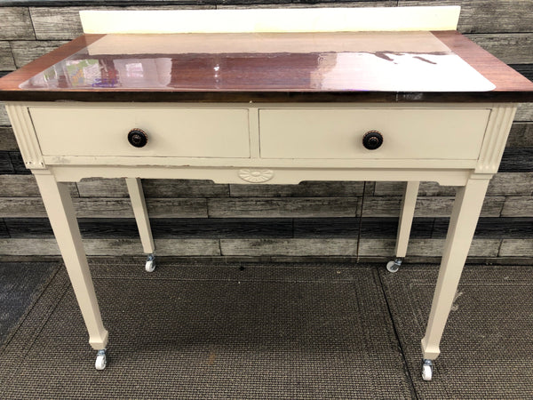 ANTIQUE DARK WOOD AND CREAM DESK ON WHEELS WITH 2 DRAWERS.