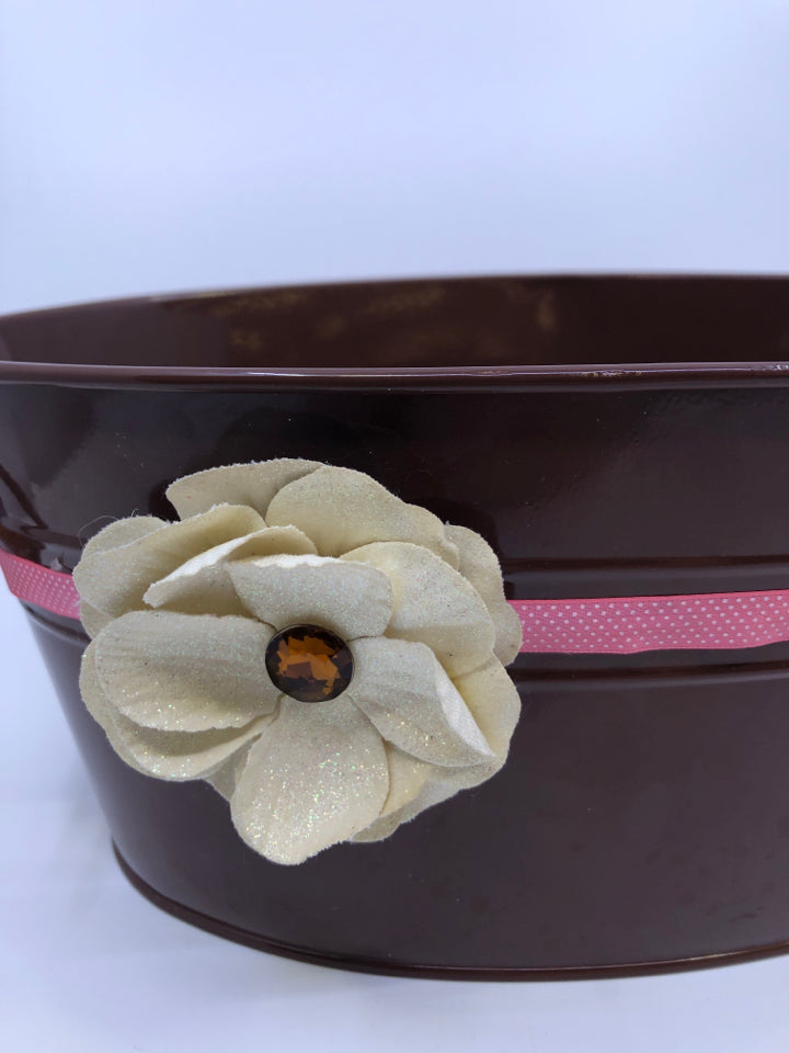 BROWN TIN OVAL BUCKET W/ SIDE HANDLES AND WHITE FLOWER.
