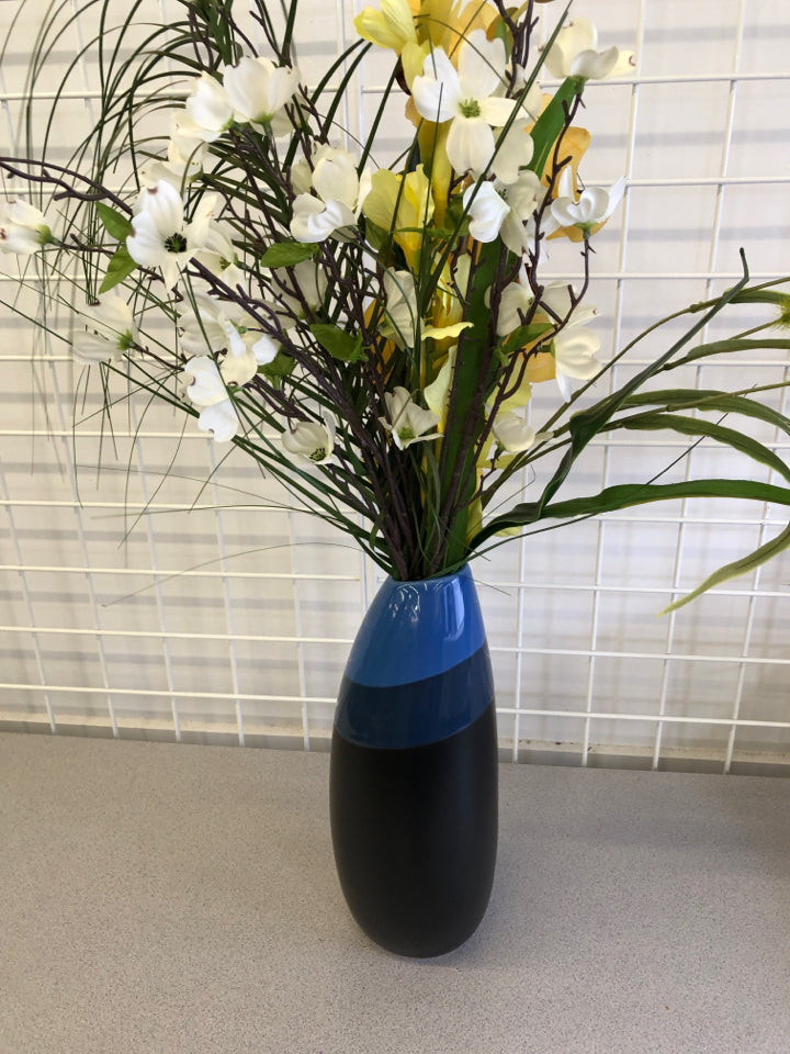 BLUE AND BLACK VASE WITH YELLOW AND WHITE FLOWERS.